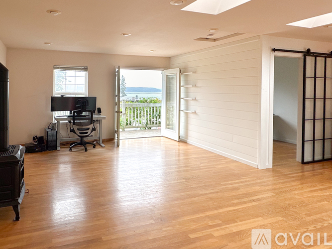 A spacious room with wooden floors and a large window.