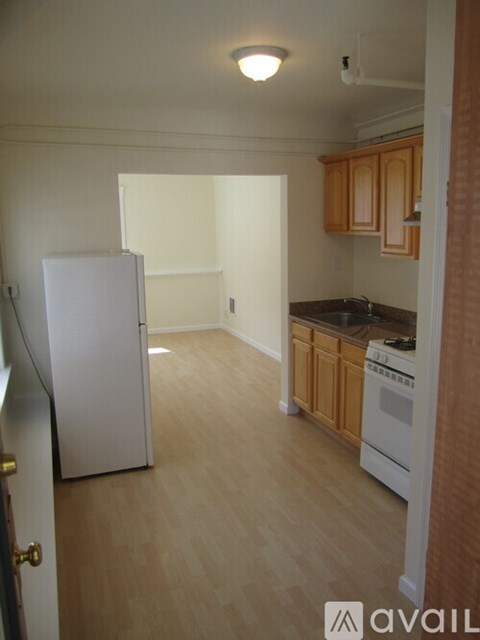A kitchen with a white refrigerator and wooden cabinets.