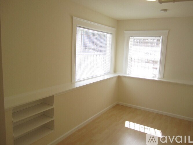 A room with two windows and wooden flooring is available.