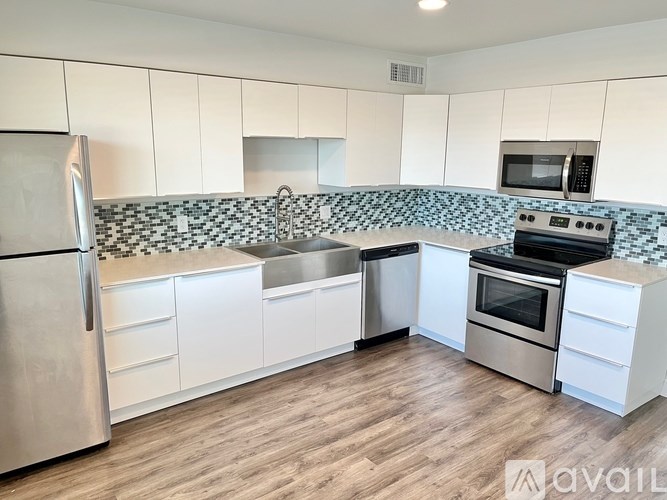 A kitchen with white cabinets and a stainless steel refrigerator.