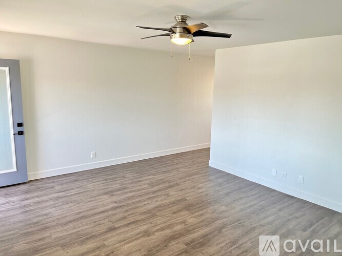 A room with a ceiling fan and light fixture, and a door on the left.