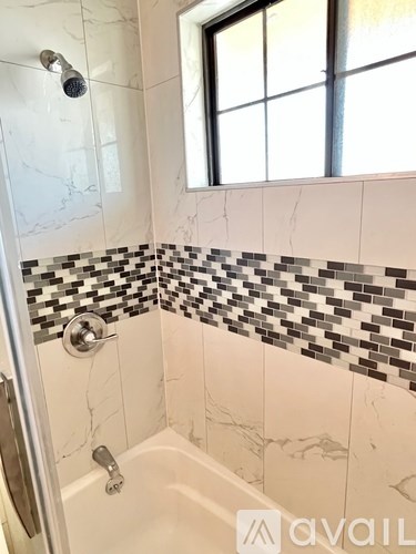 A bathroom with a black and white tiled shower area.