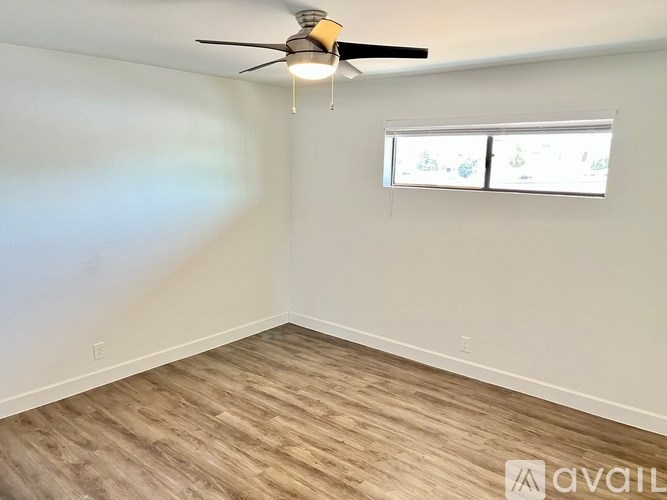 A room with a ceiling fan and a window with blinds.
