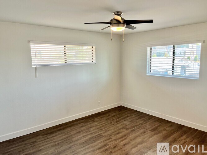 A room with a ceiling fan and two windows with blinds.