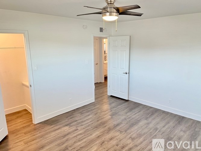 A room with a ceiling fan and wooden flooring.
