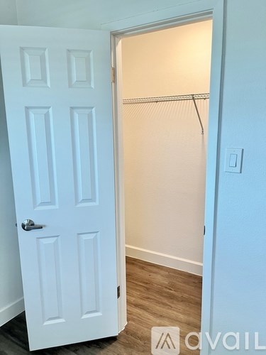 A white door is open to a room with a coat rack.