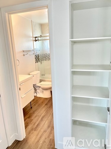 A white bathroom with a toilet, sink, and a white shelving unit.