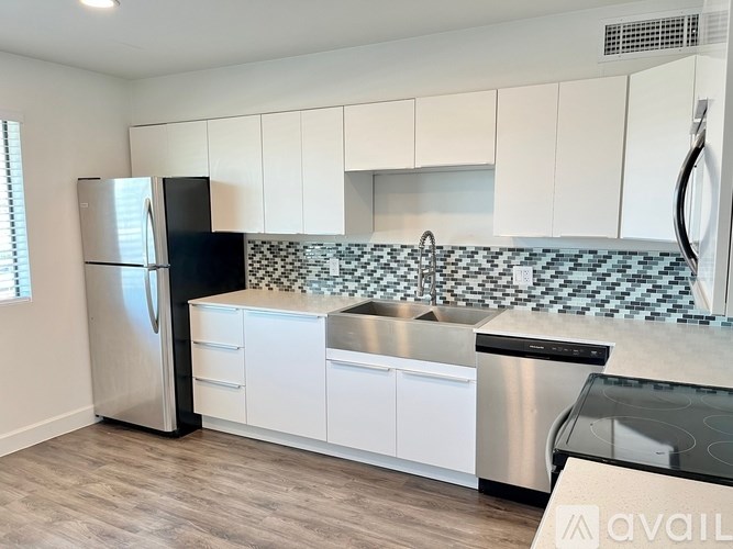A kitchen with white cabinets and a black fridge.