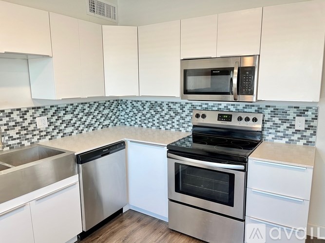 A kitchen with white cabinets and a black and white tiled backsplash.