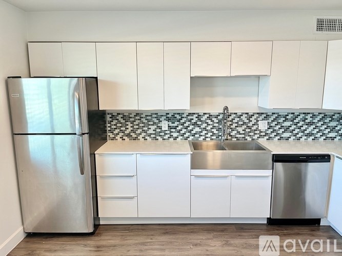 A kitchen with a stainless steel refrigerator and a checkered backsplash.