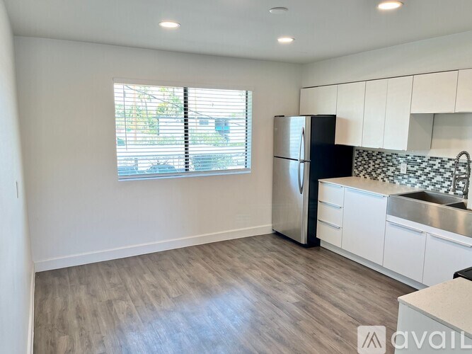 A kitchen with a black fridge and white cabinets.