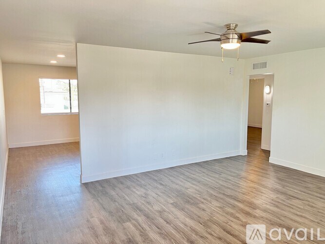 A spacious room with a ceiling fan and light, and a door on the right.
