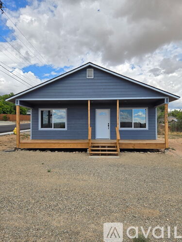 A small blue house with a porch and a single door.