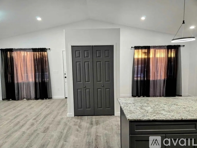 A room with a large door and two windows with curtains.