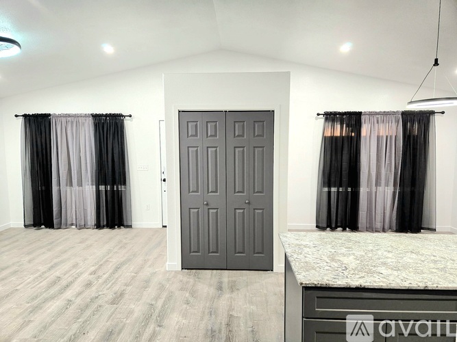 A room with a grey door, curtains, and a marble countertop.