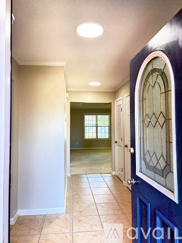 A hallway with a blue door and a window in the background.