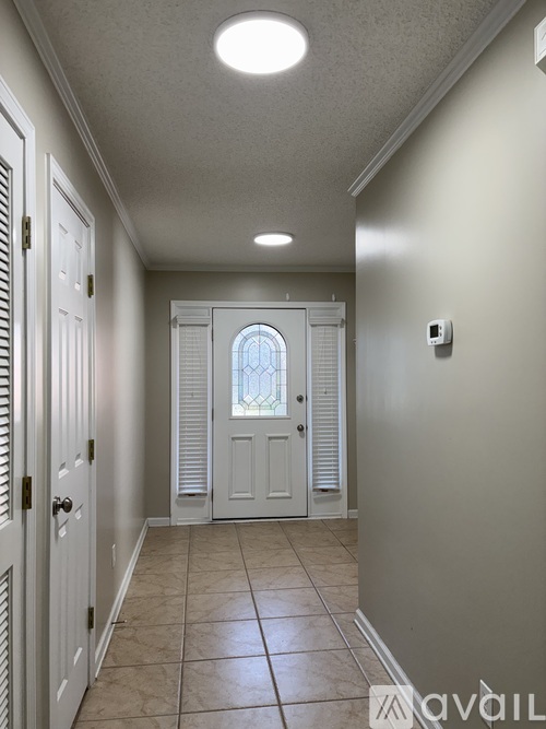 A hallway with a white door and a window.