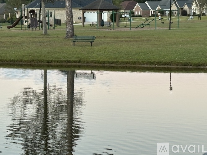 A park with a pond, a slide, a bench and a playground.