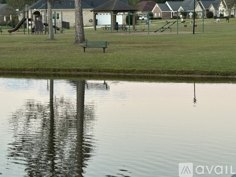 A park with a pond, a slide, a bench and a playground.