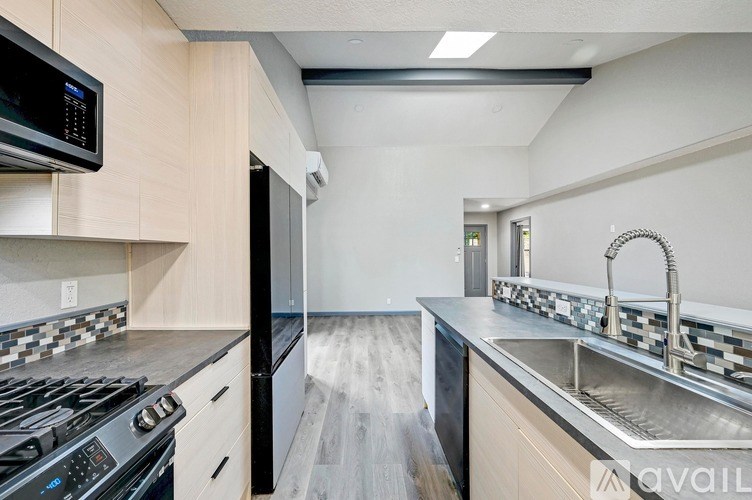 A modern kitchen with a black stove top oven and a black microwave above the counter.