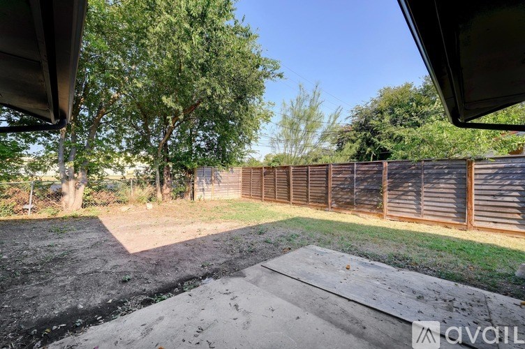 A backyard with a wooden fence and a dirt area.
