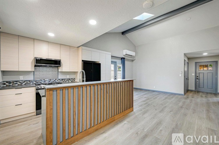 A modern kitchen with a wooden railing and a grey door.