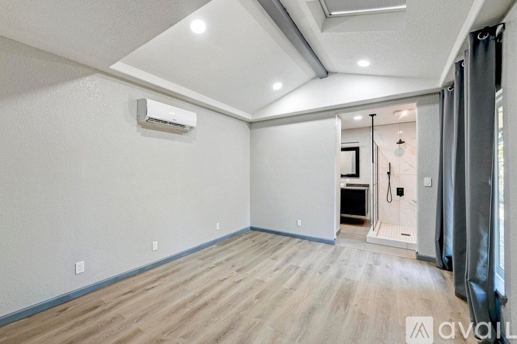 A room with a white wall and a window with a curtain.