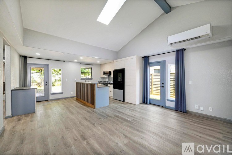 A spacious living room with a kitchen area in the background.