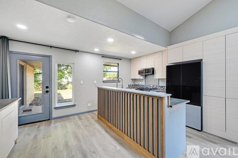 A modern kitchen with a wooden counter and a black fridge.