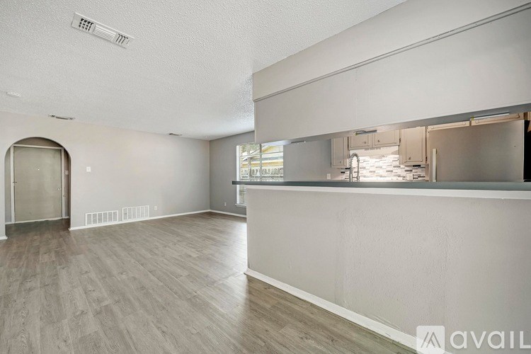 A spacious room with a bar area and a doorway leading to another room.