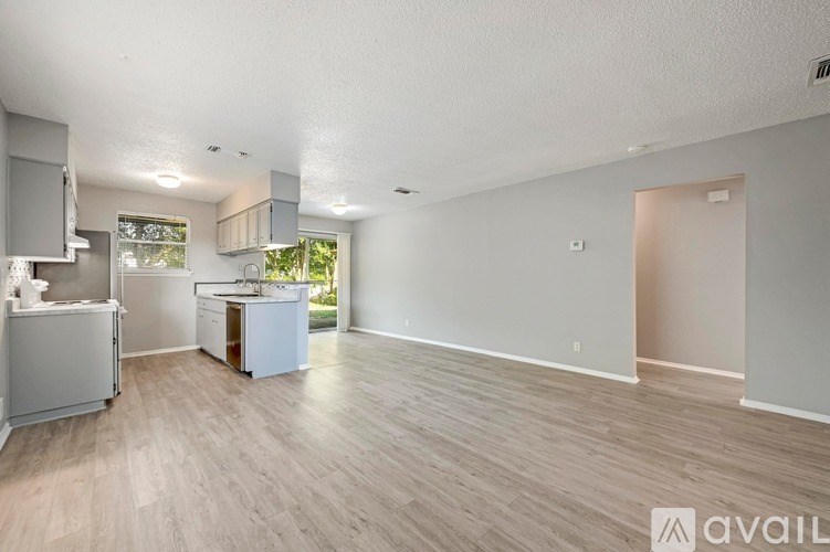 A spacious living room with a kitchen area in the background.