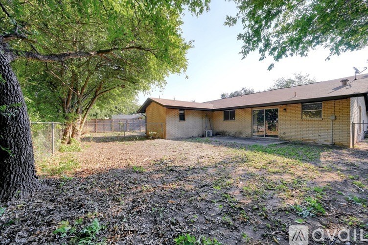 A house with a fenced backyard and trees.