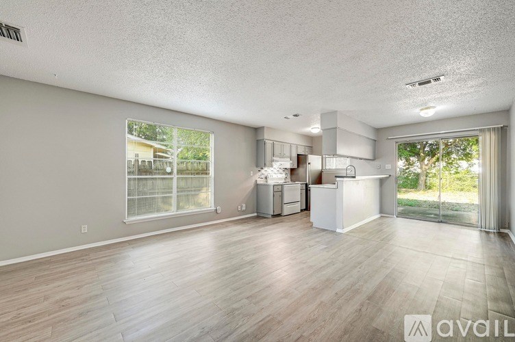 A spacious living room with a kitchenette in the background.