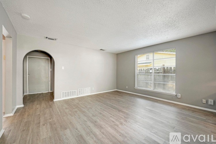 A spacious room with wooden flooring and a large window.