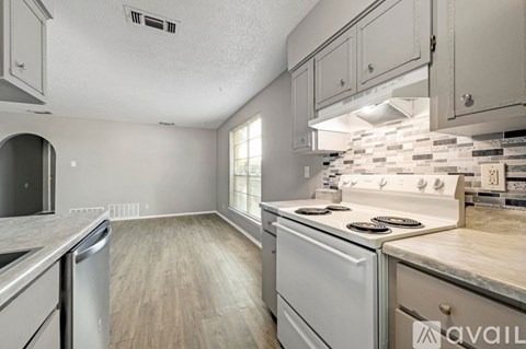 A kitchen with a white stove top oven and a white dishwasher.