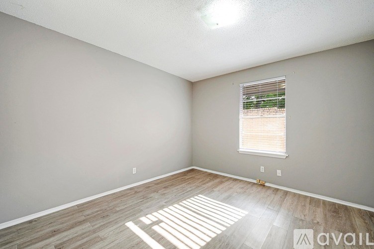 A room with wooden flooring and a window with blinds.