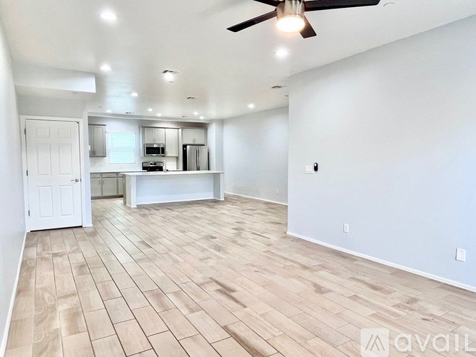 A spacious room with a ceiling fan and wooden flooring.