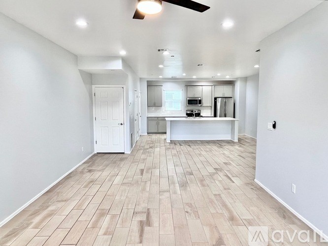 A spacious room with wooden flooring and a ceiling fan.