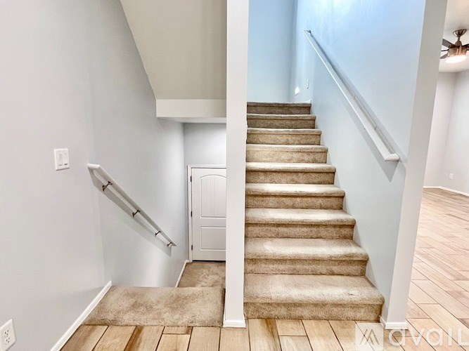 A staircase with a beige carpeted runner and white walls.