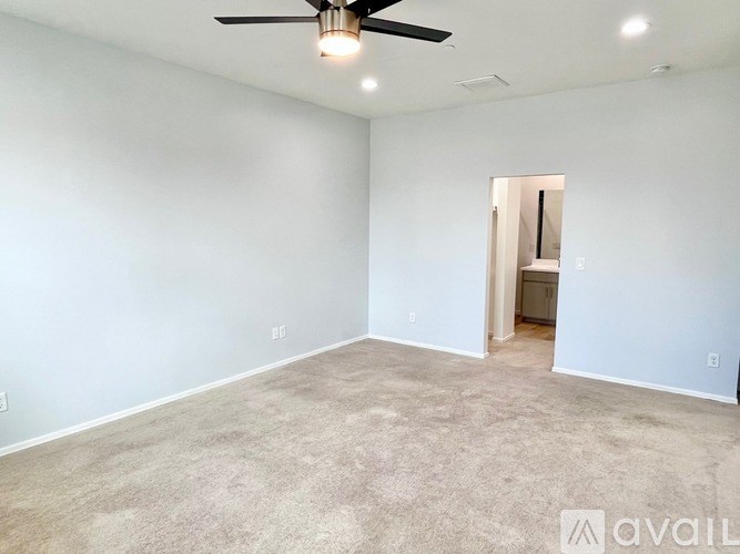 A room with a ceiling fan and carpeted floor.
