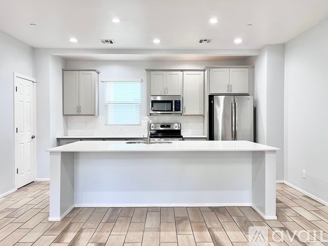 A kitchen with white cabinets and a white island.