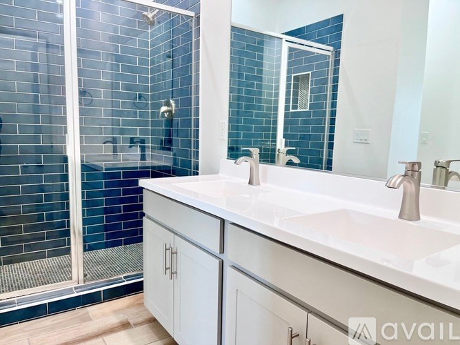 A bathroom with a white sink and a blue tiled shower.