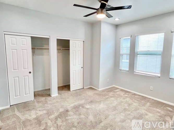A room with a ceiling fan and two closets.