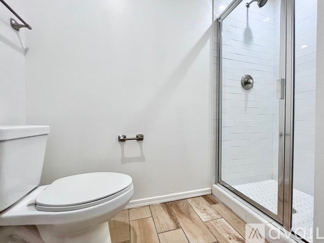 A white toilet sits in a bathroom with a walk-in shower.