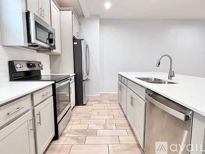 A kitchen with a black refrigerator and white countertops.