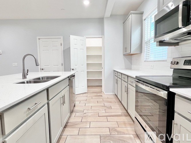 A kitchen with white cabinets and a black counter top.