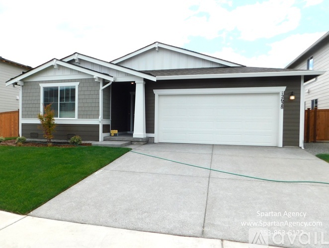 A house with a garage door is for sale through the Spartan Agency.