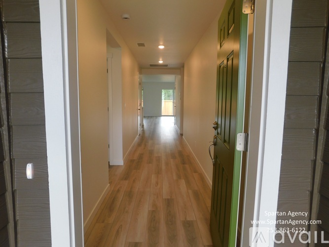 A long hallway with wood floors and white walls.