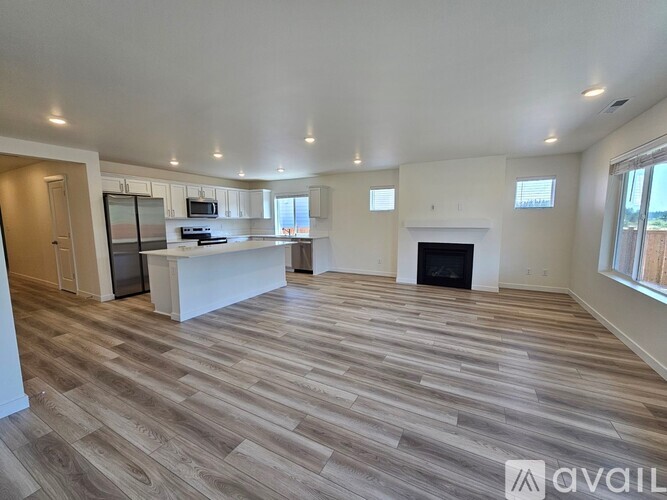 A spacious living room with a fireplace and a kitchen area in the background.