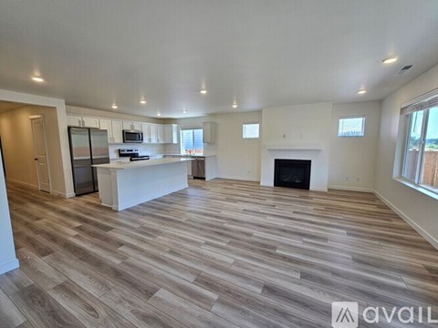 A spacious living room with a fireplace and a kitchen area in the background.